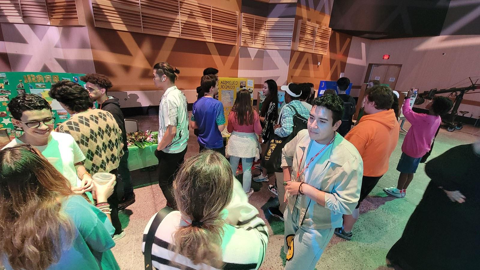 A crowd of people standing and talking around booths representing different countries at the Cultural Festival.