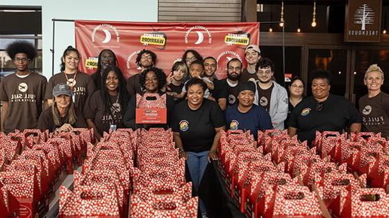 满帆 volunteers and members of the Agape Roots Foundation pose with dozens of "Thrive Pack" care packages.