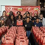 满帆 volunteers and members of the Agape Roots Foundation pose with dozens of "Thrive Pack" care packages.