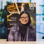 A copy of “Graphic 设计 USA” magazine depicting a woman wearing glasses and a jacket stands atop a white table.