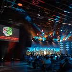 Attendees sit in the Full Sail Live venue. Screens with a lizard robot logo and the words BSides Orlando 2023: Rise of the Robots are on either side of the stage.